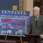 Senator Cassidy on the U.S. Senate floor with sign about fentanyl deaths