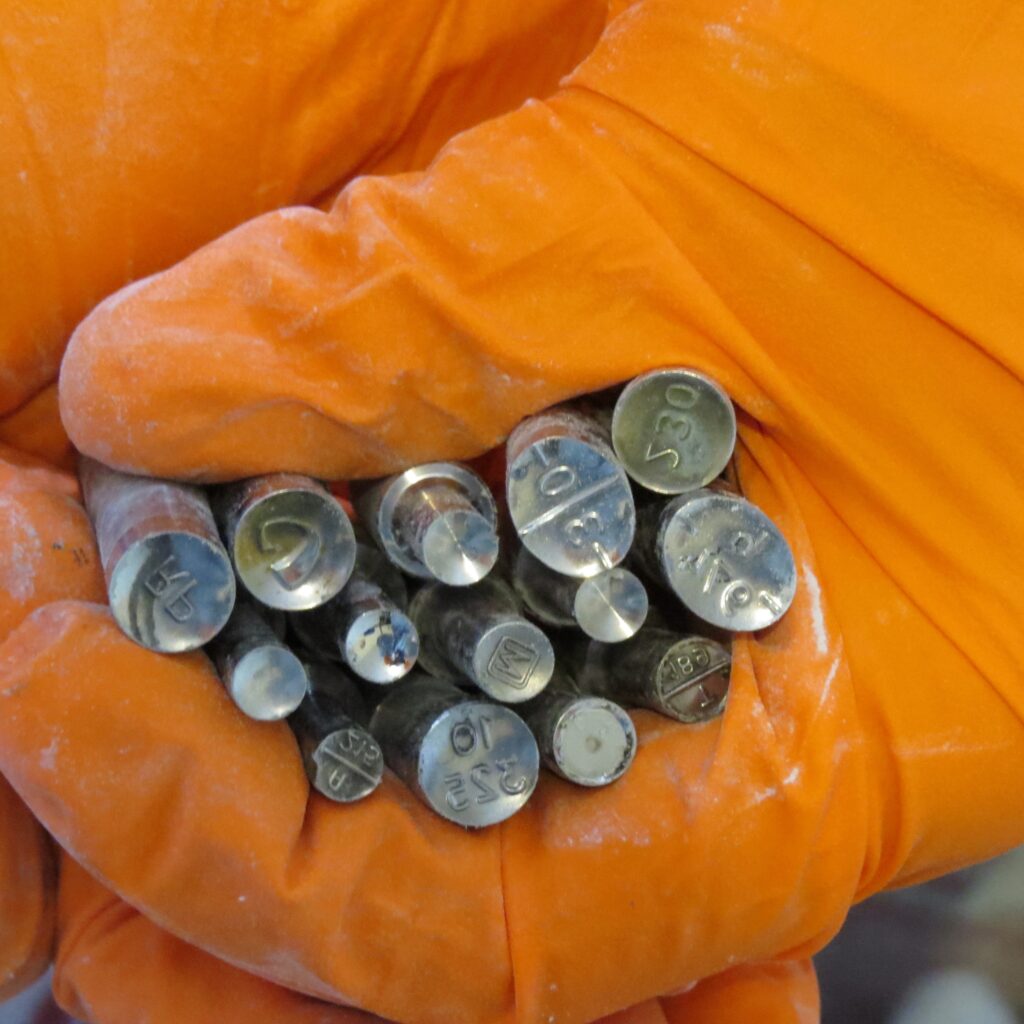 An orange gloved hand grasps more than a dozen pill molds.